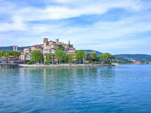 Il borgo più bello del Lago Trasimeno, con le sue case colorate e torri medievali, si specchia nelle acque azzurre.