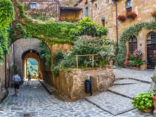 Un vicolo fiorito in uno dei 10 borghi più belli d'Italia, con archi coperti di edera e scorci panoramici.