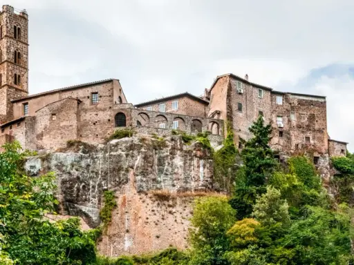 Un borgo medievale arroccato su una rupe, con un'alta torre campanaria. Un esempio dei borghi più belli del Lazio, immerso nel verde.