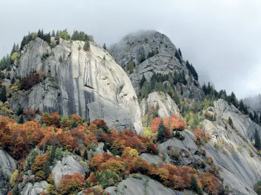 Val di Mello: maestose rocce grigie e boschi autunnali dai colori caldi, un paesaggio mozzafiato da scoprire.
