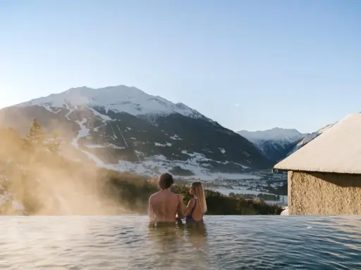 Coppia in una piscina termale con vista sulle montagne innevate. Un'oasi di relax, perfetta per chi cerca terme vicino Milano.