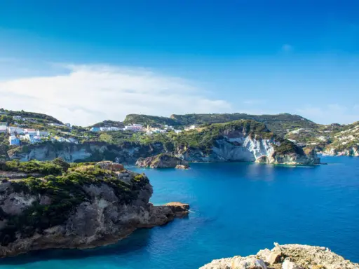 Panoramica della **cala dell'acqua a Ponza**, con case colorate aggrappate alla collina e un mare blu intenso.