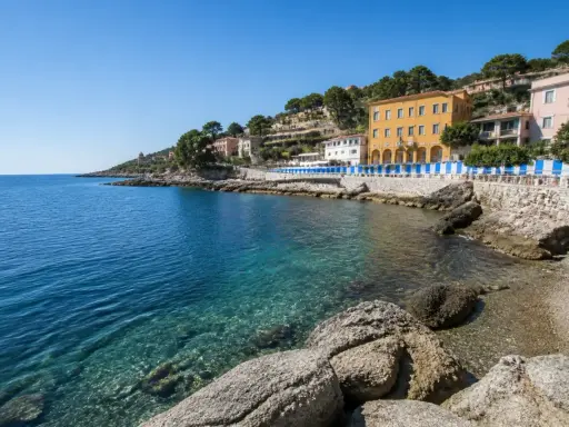 Acque cristalline e case colorate lungo la costa, un angolo di paradiso tra le calette di Porto Santo Stefano.