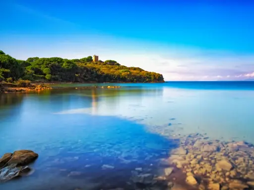 Torre medievale su una collina verdeggiante, con acque cristalline che lambiscono le **punta ala spiagge più belle**.