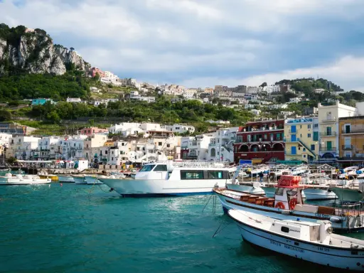 Barche nel porto di Capri, con la città arroccata sulla collina. Un ottimo punto di partenza per capire come raggiungere Capri da Napoli.