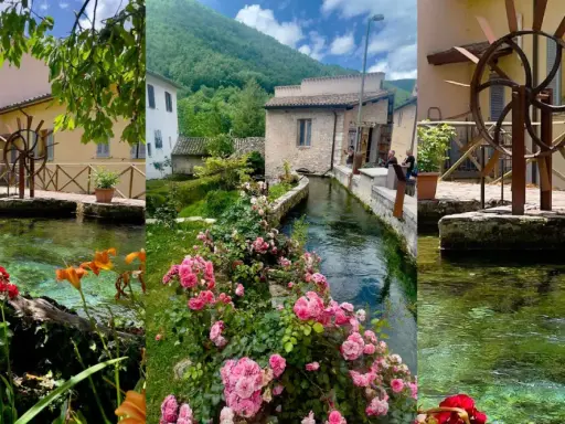 Borghi vicino Foligno: un ruscello attraversa un villaggio con mulini ad acqua, case antiche e fiori colorati.