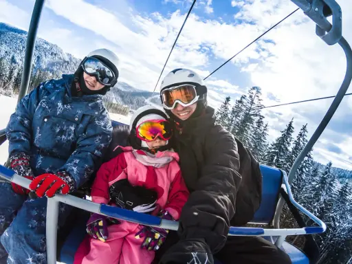 Famiglia felice in seggiovia, pronta per sciare. Ottima meta per chi cerca dove andare a sciare vicino Milano.