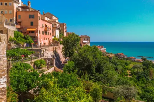 Case colorate affacciate sul mare Adriatico, un panorama mozzafiato del grottammare centro storico con giardini lussureggianti e un cielo azzurro intenso.