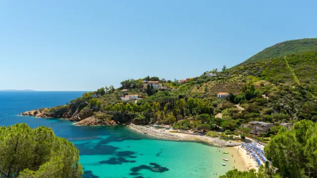 In Toscana c'è il mare, con una baia cristallina, una spiaggia attrezzata e case arroccate sulla collina verdeggiante.