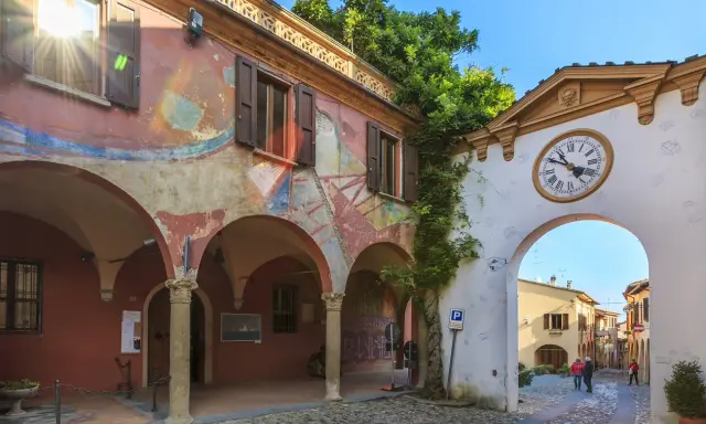 Un angolo suggestivo tra i borghi da visitare in Romagna. Archi affrescati, un portale con orologio e un vicolo acciottolato invitano alla scoperta.