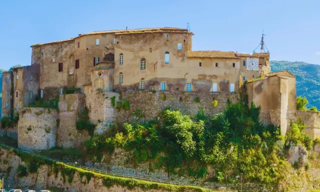 Antico castello su una collina, uno dei borghi medievali vicino Roma, con un grande orologio sulla torre.