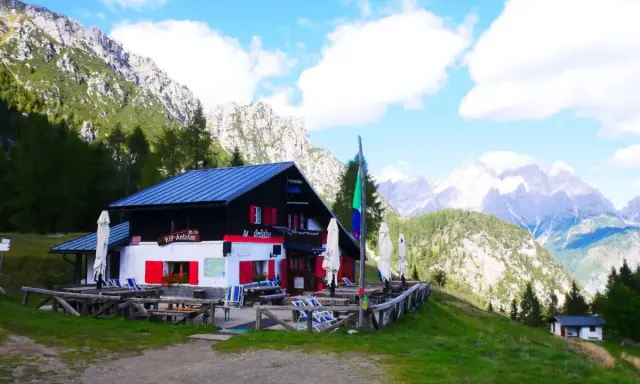 Rifugio Antelao, con le sue persiane rosse, accoglie i visitatori anche in ottobre, immerso in un paesaggio alpino mozzafiato.