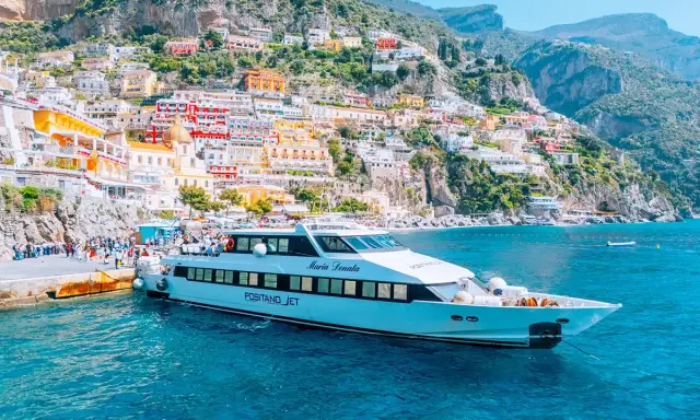 Il Positano Jet attracca al molo, con le case colorate della Costiera Amalfitana sullo sfondo.