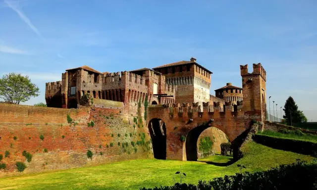 Castello Sforzesco, uno dei borghi belli vicino Cremona, con mura in mattoni rossi, ponti ad arco e fossato verde.