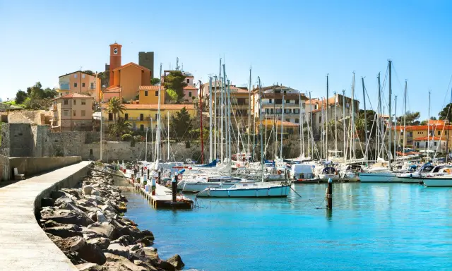 Porto turistico con barche a vela ormeggiate e case colorate che si affacciano sul mare, nel cuore del talamone centro storico.