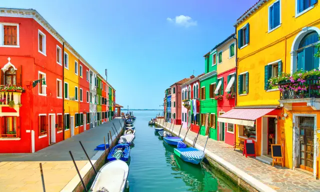 Colorate case affacciate su un canale con barche ormeggiate, un'incantevole scena di **Murano e Burano**.