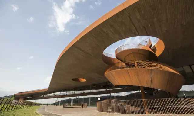 Architettura moderna di cantine toscana famose, con scale a chiocciola in corten e ampie vetrate che riflettono il paesaggio collinare.