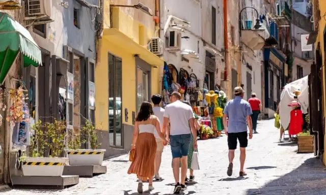 Passeggiata in un vicolo di Procida, tra negozietti colorati e case bianche. Perfetto per capire come muoversi a Procida a piedi.