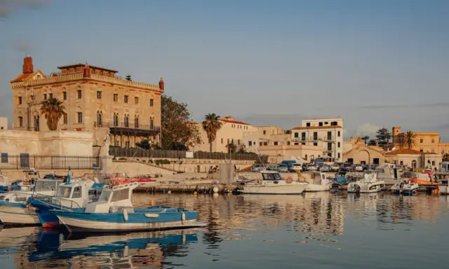 Porto di Favignana con barche ormeggiate e edifici storici. Per sapere come arrivare a Favignana, guarda questo porto!