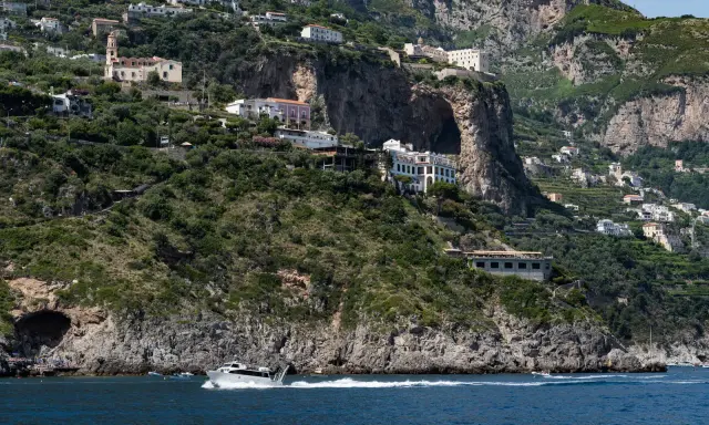 Un traghetto da Amalfi a Positano sfreccia nel mare blu, con case bianche aggrappate alle scogliere verdi.