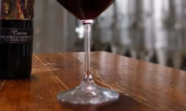 Bottiglie di Vino Nobile di Montepulciano e un calice di vino rosso, pronti per una degustazione vini toscana.