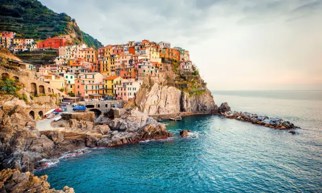 Manarola, uno dei borghi italiani da visitare, si aggrappa alla scogliera con le sue case colorate che si tuffano nel mare blu.