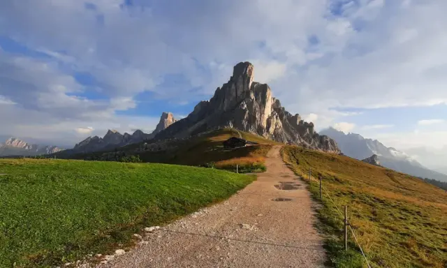 Sentiero per escursioni al Passo Giau, con imponenti vette rocciose e un rifugio alpino.