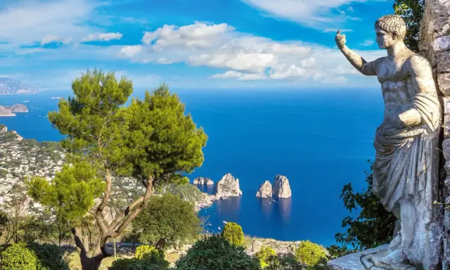 Statua antica guarda il mare blu intenso e i Faraglioni, icona dell'isola vicino Capri.
