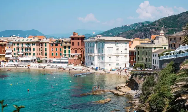 Colorate case affacciate su una spiaggia affollata e un mare turchese, tipico della riviera di Levante.