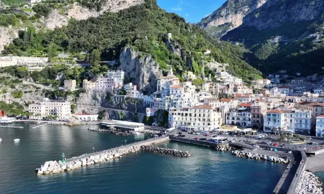 La **conca dei Marini** si apre sul mare blu, con case colorate aggrappate alla scogliera verdeggiante.