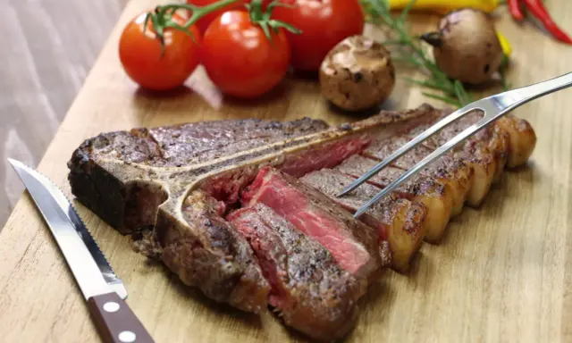 Una succulenta bistecca alla fiorentina, tagliata e pronta per essere gustata. Perfetta per scoprire dove mangiare la fiorentina a Firenze.