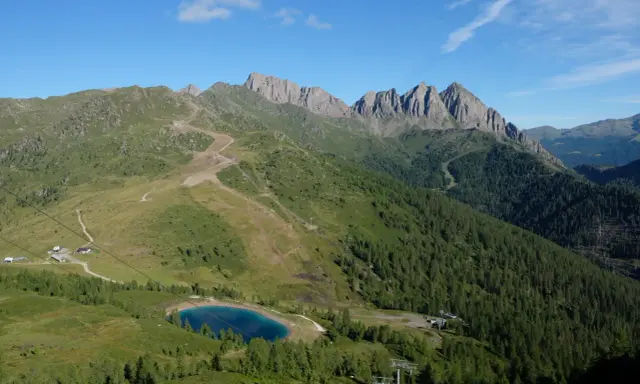 Panorami alpini con sentieri per passeggiate facili vicino a Trento, un lago azzurro e cime rocciose.