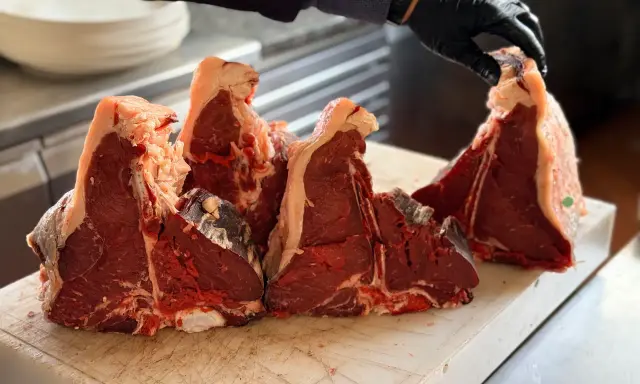 Maneggiare con cura la bistecca fiorentina a Firenze, pronta per essere grigliata.