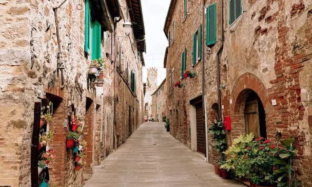Un vicolo fiorito a Campagnatico, con case in pietra e persiane verdi. Un luogo incantevole da scoprire, tra scorci pittoreschi e storia.
