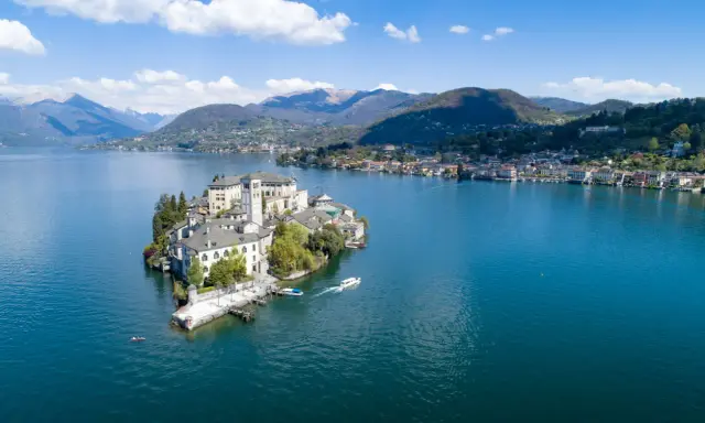 Isola di San Giulio, una gemma nel lago d'Orta, con la città sul mare nord Italia sullo sfondo.