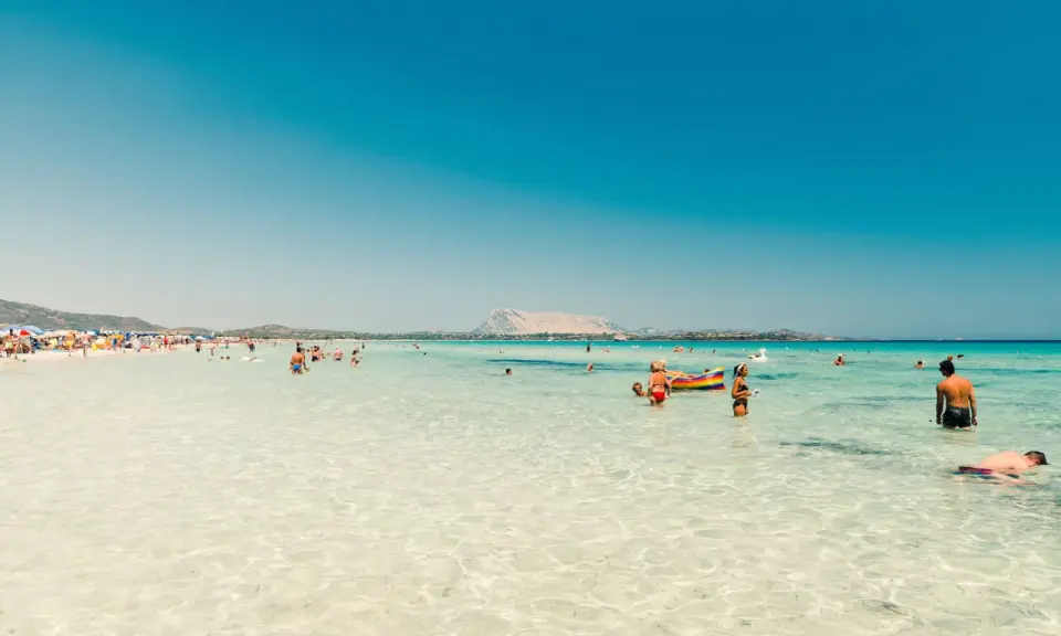 Acque cristalline e gente felice in spiaggia, forse qual è la parte più bella della Sardegna? Un paradiso azzurro.