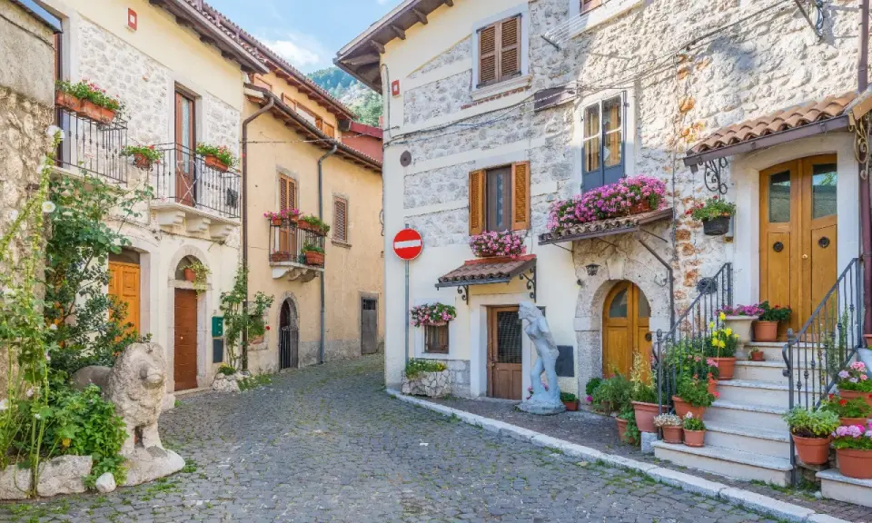 Antica via acciottolata tra **borghi Abruzzo sul mare**, con case in pietra e fiori colorati sui balconi.