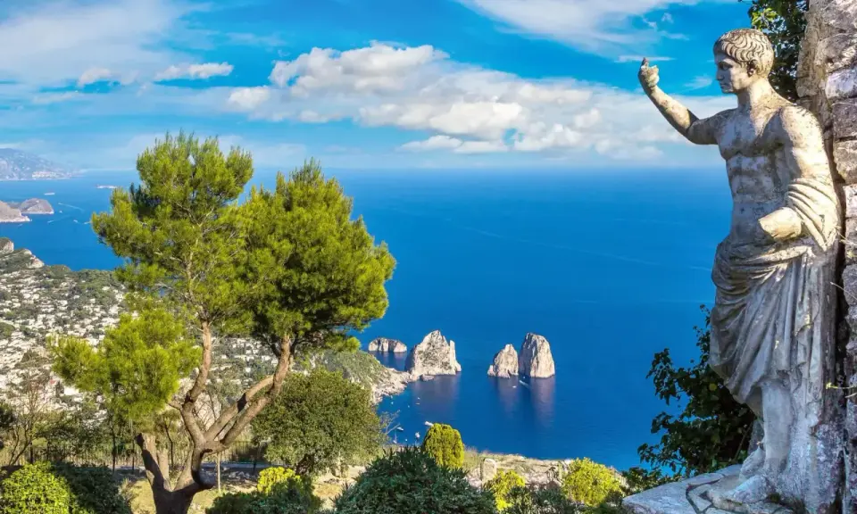 Statua antica guarda il mare blu intenso e i Faraglioni, icona dell'isola vicino Capri.
