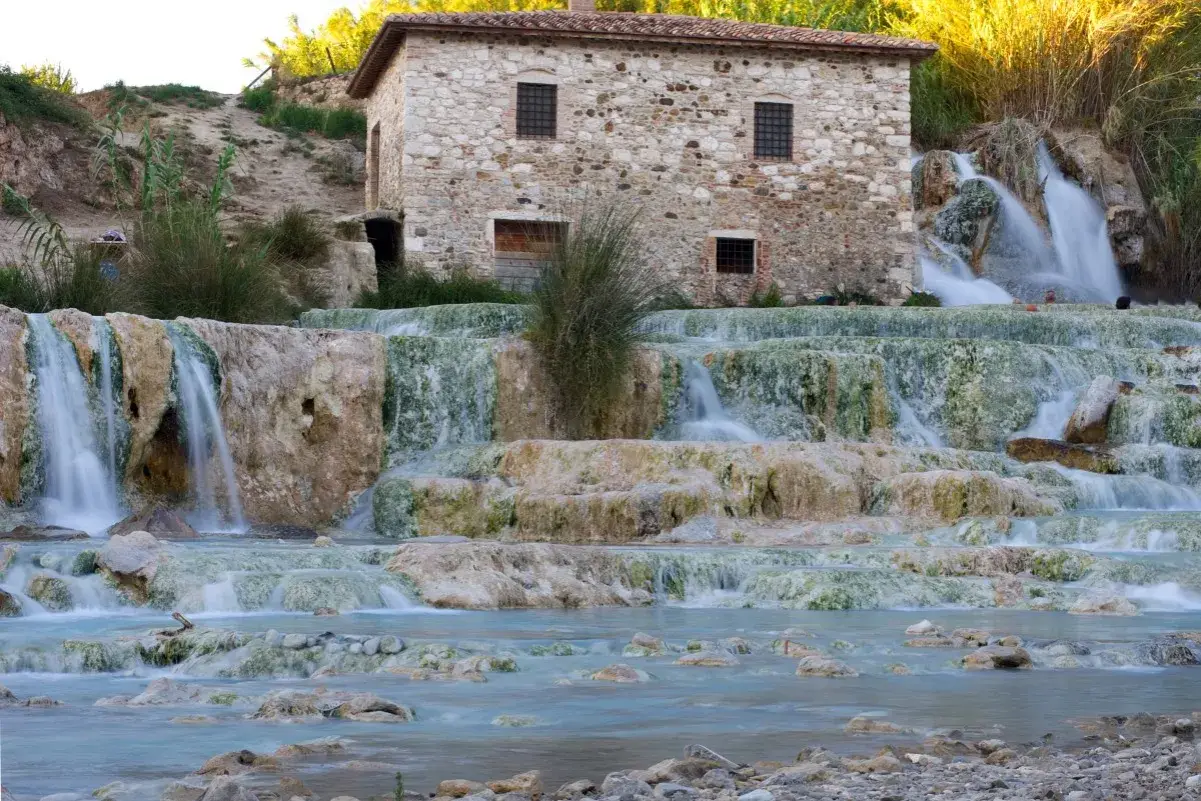 Cascate termali naturali con un antico mulino in pietra, un'oasi di benessere nel cuore delle terme centro Italia.