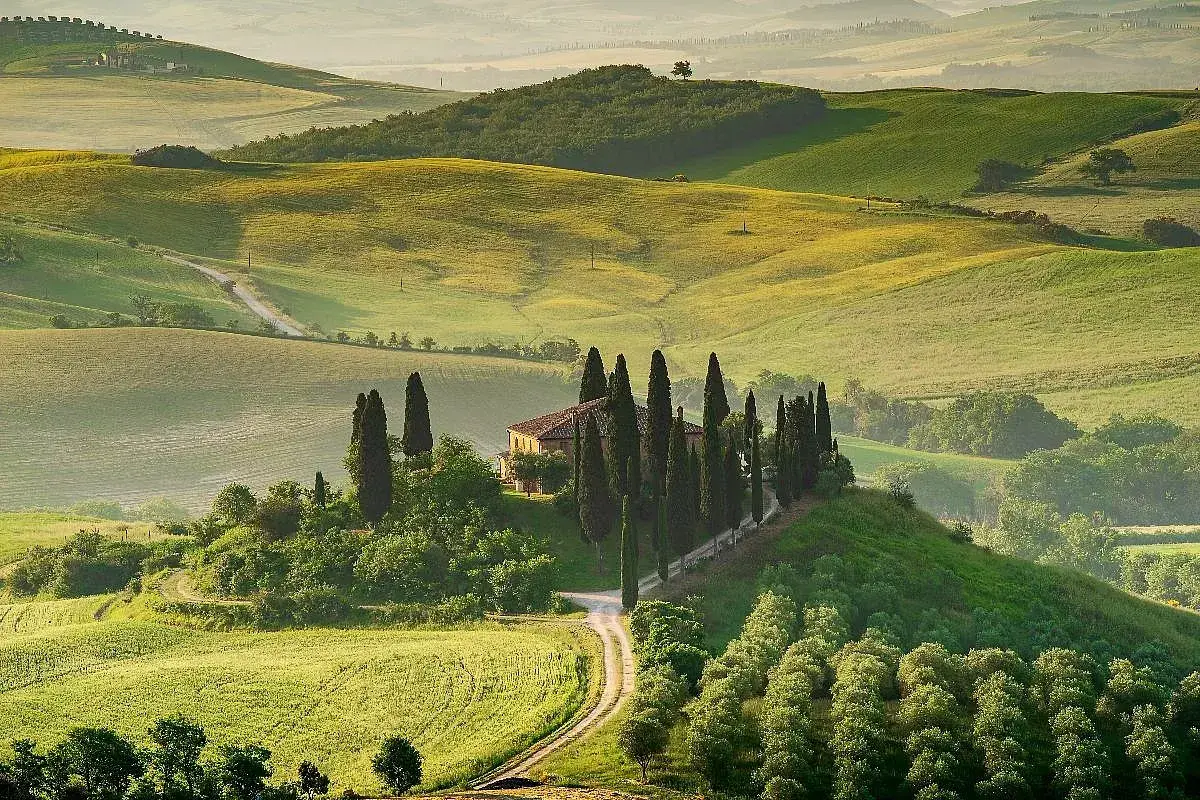 Colline toscane con cipressi e casale, un'immagine iconica dei borghi da visitare in Toscana.