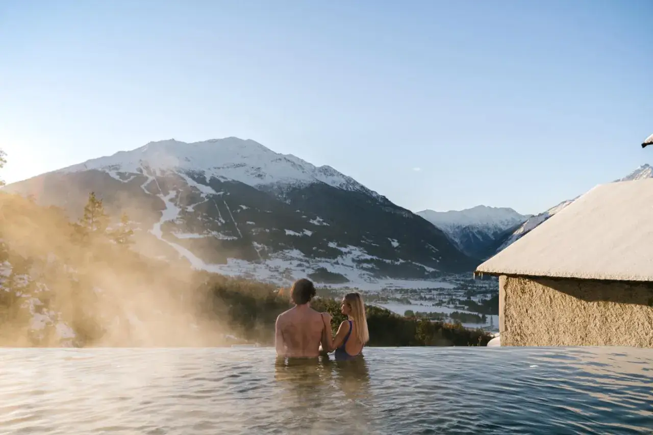 Coppia in una piscina termale con vista sulle montagne innevate. Un'oasi di relax, perfetta per chi cerca terme vicino Milano.