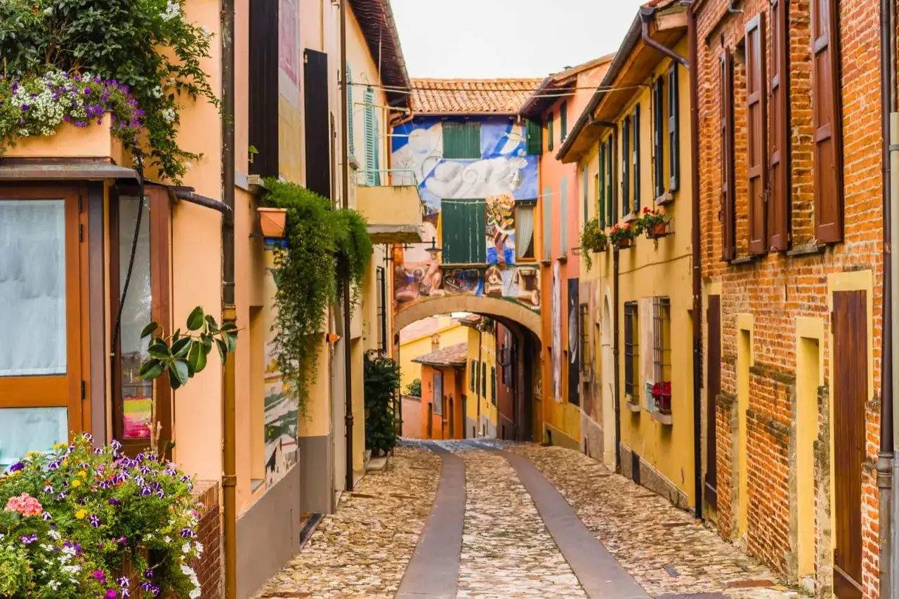Un vicolo acciottolato con case colorate e murales, un'immagine perfetta dei borghi da visitare in Romagna.