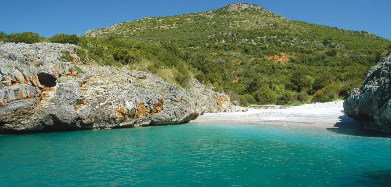 Spiaggia selvaggia con rocce e macchia mediterranea, un angolo di paradiso tra le località di mare più economiche Italia.