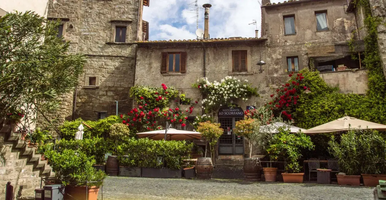 Viterbo cosa vedere in un giorno: un ristorante con rose rosse e bianche che incorniciano l'ingresso, tavolini all'aperto e un'atmosfera incantevole.