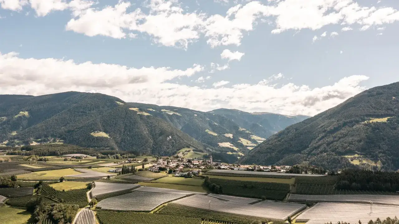 Vista aerea di Vipiteno, incastonata tra montagne verdi e campi coltivati. Un paesaggio idilliaco che mostra dove si trova Vipiteno.