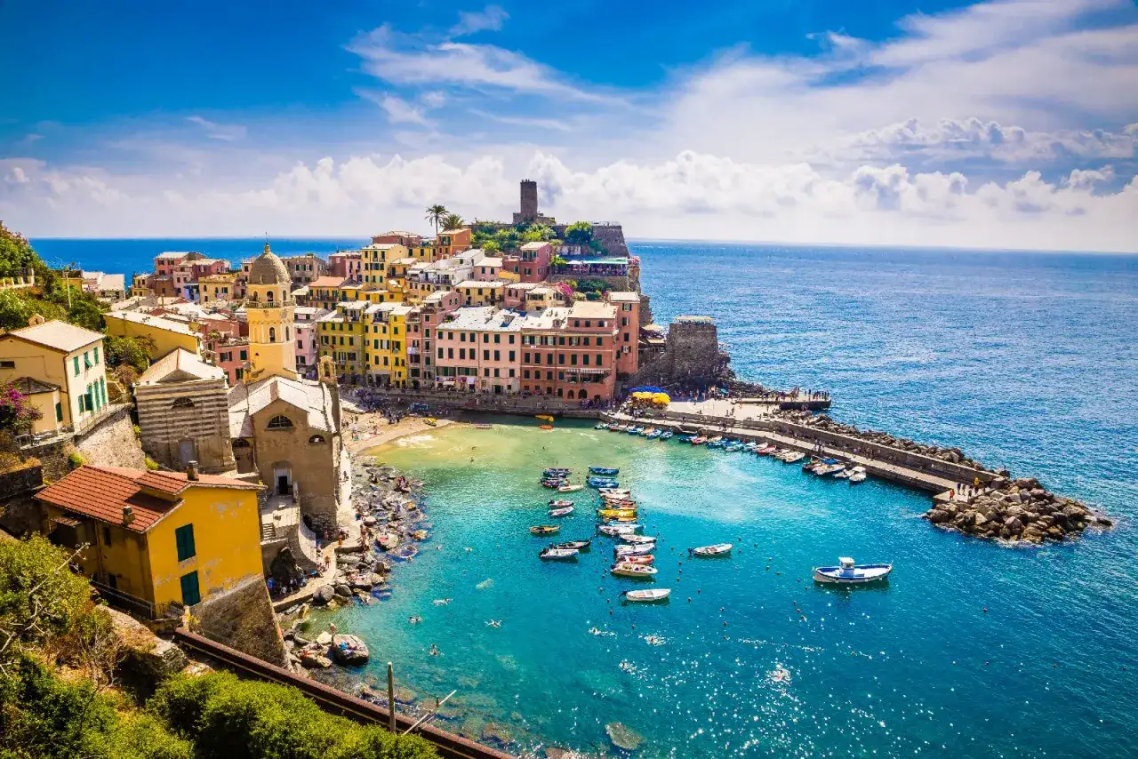 Vernazza, una delle Cinque Terre, con case colorate a picco sul mare blu e barche ormeggiate.