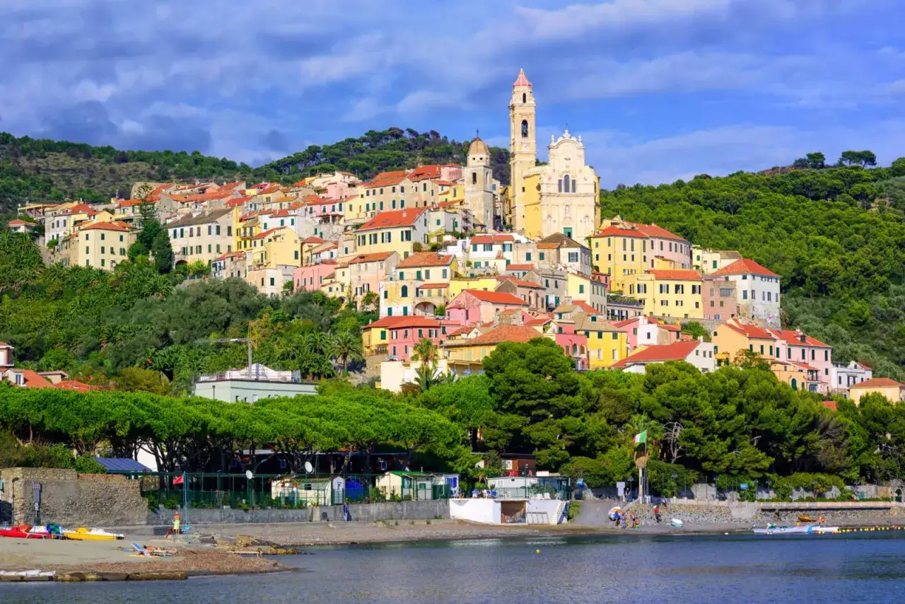 Colorati paesi sul mare in Liguria, con case aggrappate alla collina verde e una chiesa imponente.