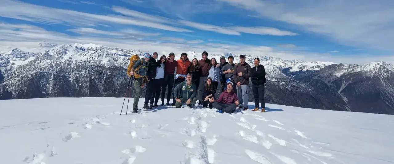 Gruppo di amici in cima a una montagna innevata, un'ottima meta per chi cerca dove ciaspolare in Piemonte.