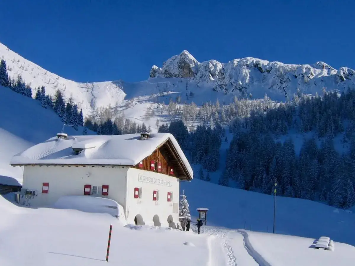 Rifugio innevato ai piedi delle Dolomiti Bellunesi, ideale per escursioni invernali.