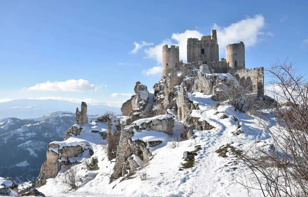 Rovine di un castello innevato su una roccia, un paesaggio suggestivo tra i borghi vicino L'Aquila.